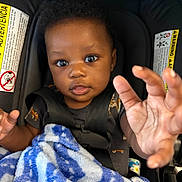 Jarriett joined the competition — help win amazing prizes! baby, child, car_seat, blanket, hand, face, curly_hair, seatbelt, clothing, indoor, infant, expression, cute, person, portrait, young, sitting, blue, black_hair, looking