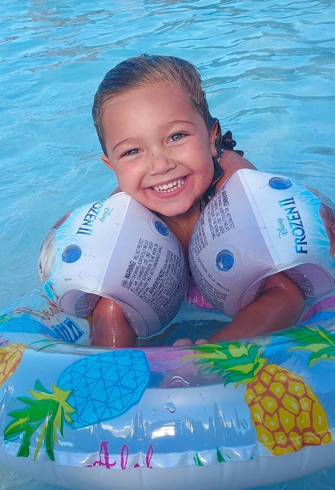 Jenna participe au concours pour gagner de l'argent avec cette photo : ananas, aqua, azure, baby_float, blue, chest, child, fun, happy, joy, leisure, pattern, person, personal_protective_equipment, pineapple, recreation, smile, summer, swimming_pool, toddler