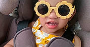 Zaniyah-Ann joined the competition — help win amazing prizes! accessory, baby, car, car_seat, child, clothing, curly_hair, cute, flower_shaped, hands, happy, indoor, person, portrait, safety_harness, seatbelt, smiling, sunglasses, toddler, yellow