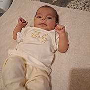 Kali is registered to the contest to win money with this photo: baby, infant, towel, clothing, lying_down, face, smile, hand, arm, leg, bottle, baby_lotion, fabric, pattern, bed, soft, cute, person, indoor, comfort