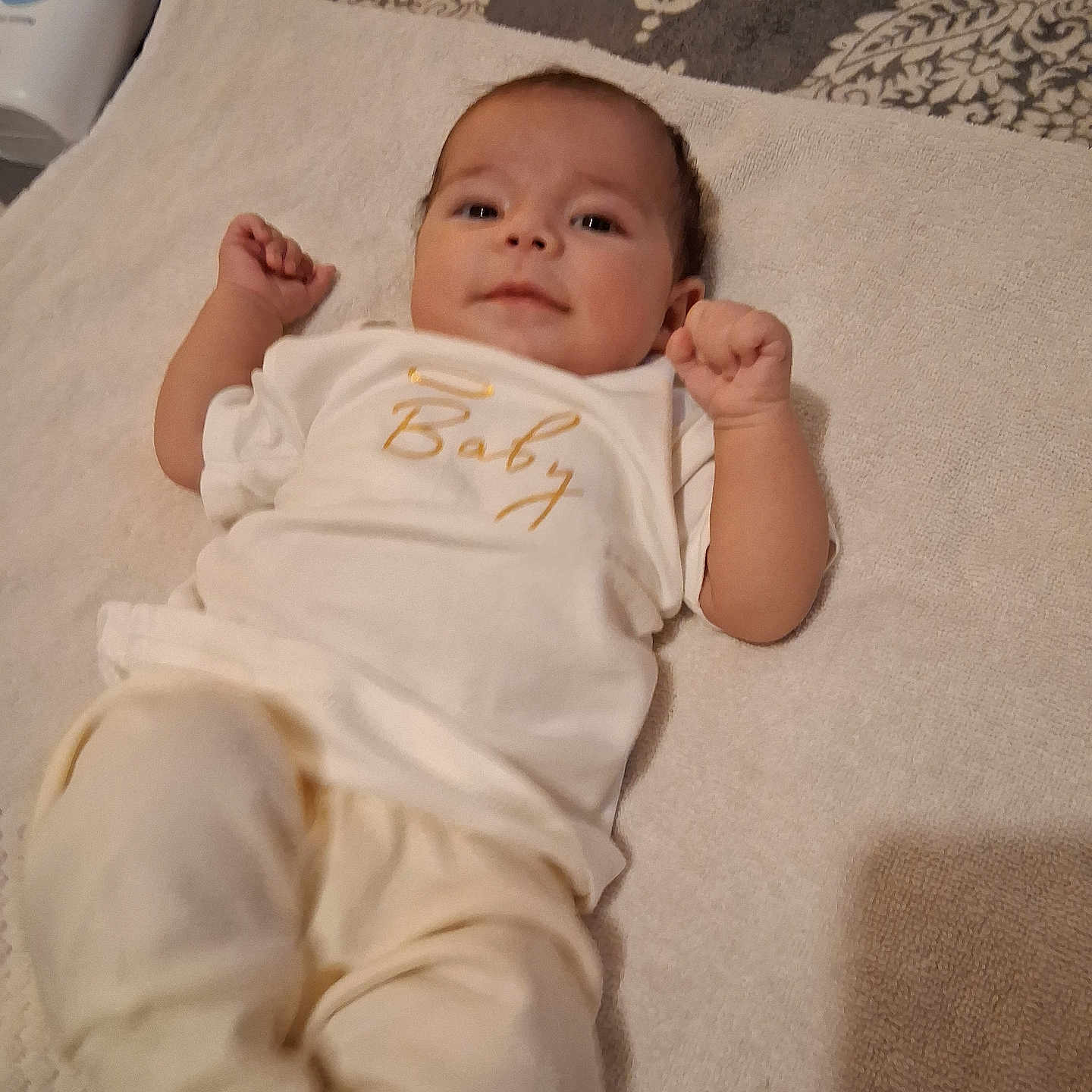 Kali is registered to the contest to win money with this photo: arm, baby, baby_lotion, bed, bottle, clothing, comfort, cute, fabric, face, hand, indoor, infant, leg, lying_down, pattern, person, smile, soft, towel