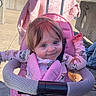 Nora is registered to the contest to win money with this photo: baby, blanket, blue_eyes, child, clothing, concrete, daylight, face, hand, happy, nature, outdoor, pajamas, person, pink, seatbelt, smile, stroller, sunny, toddler