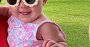 Berkley joined the competition — help win amazing prizes! accessory, adult_hand, baby, building, child, cute, fashion, floral_clothing, grass, headband, mural, outdoor, park, person, pink, red_sweater, smiling, striped_shorts, sunglasses, sunny_day