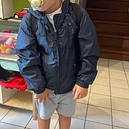 Kayden a rejoint le concours — aidez-le/la à gagner de superbes lots ! child, boy, pacifier, jacket, shorts, shoes, indoor, tile_floor, toys, backpack, stairs, home, curious, standing, casual_clothing, young, person, portrait, daylight, expression