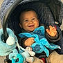 Lyam participe au concours pour gagner de l'argent avec cette photo : baby, infant, stroller, car_seat, blanket, plush_toy, blue_blanket, smiling, happy, child, portrait, canopy, hand, fingers, seat_buckle, jacket, outdoor, pavement, toy_ring, cute