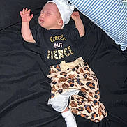 Amelia is registered to the contest to win money with this photo: baby, sleeping, infant, bed, pillow, black_bedspread, striped_pillow, clothing, hat, white_sock, leopard_print, toddler, cute, resting, child, person, indoors, soft_lighting, peaceful, nap