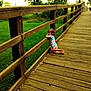 Beverly joined the competition — help win amazing prizes! bridge, casual, child, colorful_clothing, daylight, fence, grass, greenery, kneeling, nature, outdoor, peaceful, person, portrait, scenery, summer, sunlight, thoughtful, wood, young
