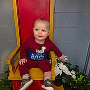 Jaxson joined the competition — help win amazing prizes! baby, child, smiling, sitting, chair, red_chair, yellow_chair, maroon_clothing, sneakers, indoor, plants, potted_plants, white_flowers, gray_wall, portrait, cute, happy, person, throne, floor