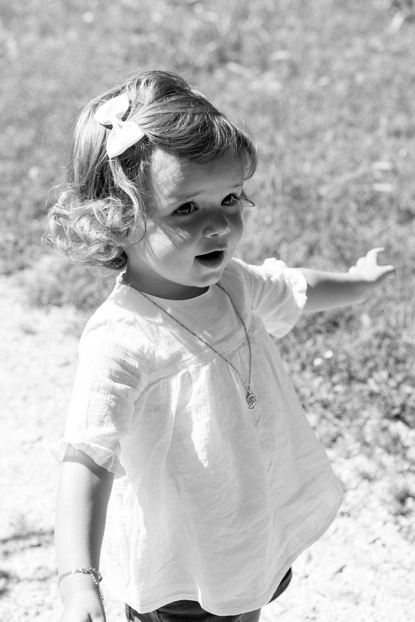 Romy participe au concours pour gagner de l'argent avec cette photo : black_and_white, blond, child, flash_photography, fun, gesture, grass, hair, hair_tie, happy, monochrome, monochrome_photography, people_in_nature, person, sand, smile, standing, style, toddler, vintage_clothing