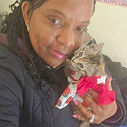 Katie is registered to the contest to win money with this photo: woman, cat, kitten, braided_hair, jacket, indoor, portrait, affection, pet, animal, cute, clothing, pink_nails, ring, poster, wall, holding, face, hand, closeup