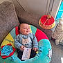 baby, child, plush_seat, couch, cake, card, indoor, person, colorful, smiling, playful, clothing, face, hand, furniture, home, decor, soft_toys, tongue_out, light