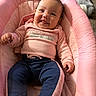 baby, infant, child, smiling, tongue_out, pink_clothing, navy_pants, cushioned_seat, pink_cushion, indoor, carpet, cute, happy, person, portrait, relaxed, babywear, baby_toys, soft_fabric, cozy