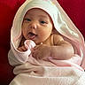 baby, infant, towel, pink, hooded_towel, tongue_out, cute, skin, hand, blanket, red_background, gray_background, cozy, wrapped, portrait, smiling, child, indoors, closeup, person