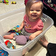 Lorelai Rain joined the competition — help win amazing prizes! toddler, child, smiling, plastic_bin, toy, stuffed_animal, floor, foot, clothing, pink_shirt, gray_pants, indoor, playtime, happy, person, hair, face, hand, sitting, colorful