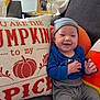 baby, smiling, couch, pillow, striped_clothing, hat, infant, indoor, decor, pumpkin, orange, blue_clothing, child, happy, cozy, portrait, home, sitting, cute, seasonal