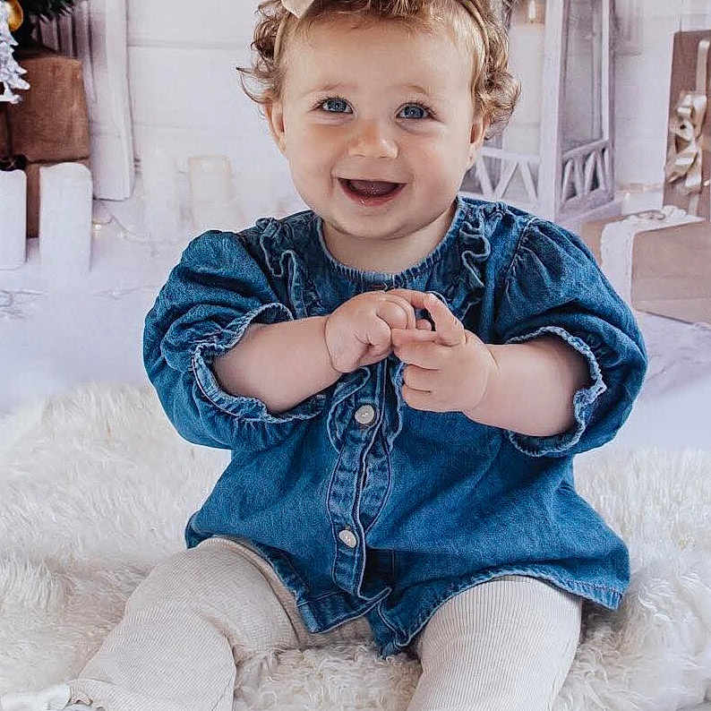 Indie joined the competition — help win amazing prizes! baby, blue_eyes, bow, child, clothing, curly_hair, cute, decor, denim, footwear, happy, holiday, indoors, infant, lantern, portrait, sitting, smiling, white_rug, wrapped_gifts