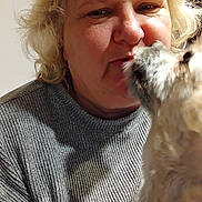 Rimpo a rejoint le concours — aidez-le/la à gagner de superbes lots ! affection, animal, blonde_hair, candid, canine, close_up, companion, curly_hair, dog, face, gray_sweater, human, indoor, interaction, kiss, love, pet, portrait, warmth, woman