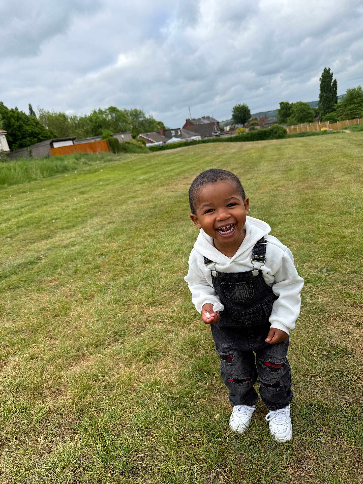 Kayden joined the competition — help win amazing prizes! child, toddler, smiling, overalls, white_hoodie, grass, outdoor, field, cloudy_sky, happy, casual_clothing, shoes, young_child, nature, greenery, playful, person, laughing, daytime, casual_style