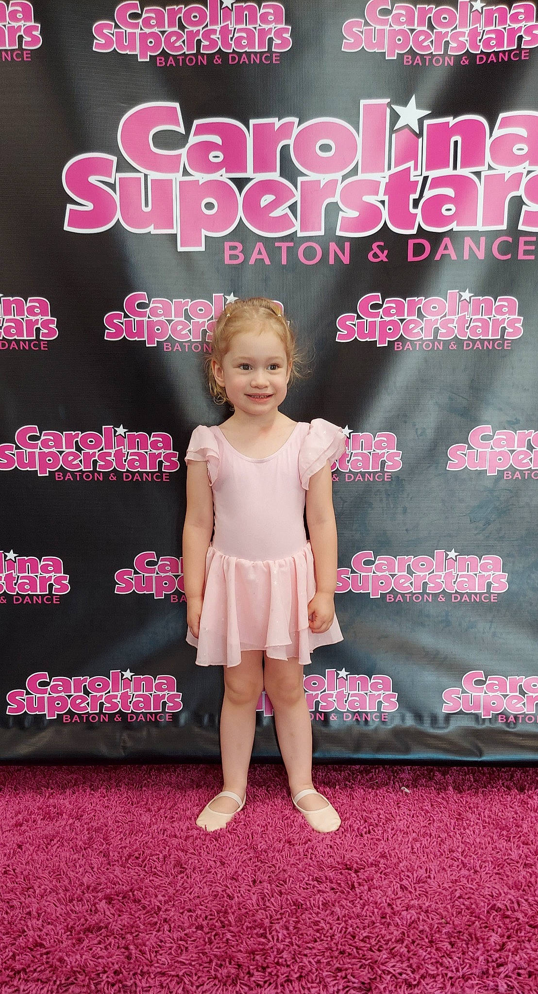 Baylee is registered to the contest to win money with this photo: baby_toddler_clothing, day_dress, dress, event, facial_expression, fashion, fashion_design, flooring, font, formal_wear, happy, joy, leg, magenta, one_piece_garment, pattern, person, pink, product, red