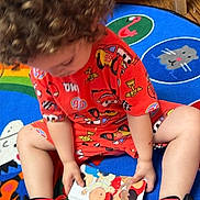 Messiah joined the competition — help win amazing prizes! child, toddler, curly_hair, red_pajamas, sneakers, picture_book, play_mat, animal_pattern, indoor, wooden_floor, colorful, toy, reading, sitting, floor, casual, cute, young_child, playtime, comfortable