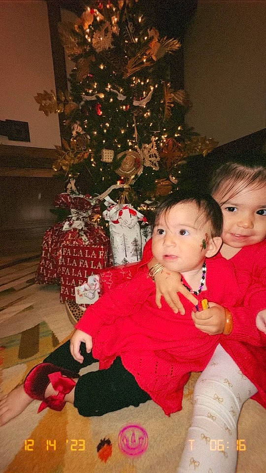 Breezy is registered to the contest to win money with this photo: baby_toddler_clothing, child, christmas, christmas_decoration, christmas_eve, christmas_ornament, christmas_tree, event, happy, holiday, holiday_ornament, lap, ornament, person, plant, red, sitting, smile, toddler, tree