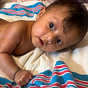 Luna is registered to the contest to win money with this photo: baby, infant, child, towel, striped_towel, skin, arm, hand, face, eyes, hair, indoors, lying_down, expression, curious, closeup, portrait, cute, newborn, soft_light