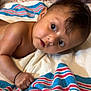 baby, infant, child, towel, striped_towel, skin, arm, hand, face, eyes, hair, indoors, lying_down, expression, curious, closeup, portrait, cute, newborn, soft_light