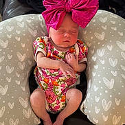 Anslee is registered to the contest to win money with this photo: newborn, baby, sleeping, pink_bow, floral_onesie, baby_pillow, heart_pattern, couch, blanket, indoor, infant, clothing, resting, cute, small_baby, relaxing, person, headwear, soft_fabric, cozy