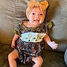 baby, child, infant, smiling, tongue_out, portrait, sitting, couch, sofa, bow_headband, headband, dress, floral_pattern, baby_clothing, indoors, home, furniture, barefoot, happy, photography