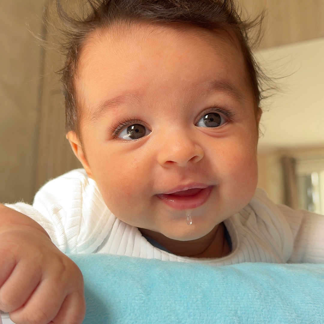 Naël participe au concours pour gagner de l'argent avec cette photo : baby, infant, drool, toy, blue_blanket, curious, face, hand, indoor, portrait, child, soft_lighting, white_clothing, closeup, cute, expression, furniture, room, smile, skin
