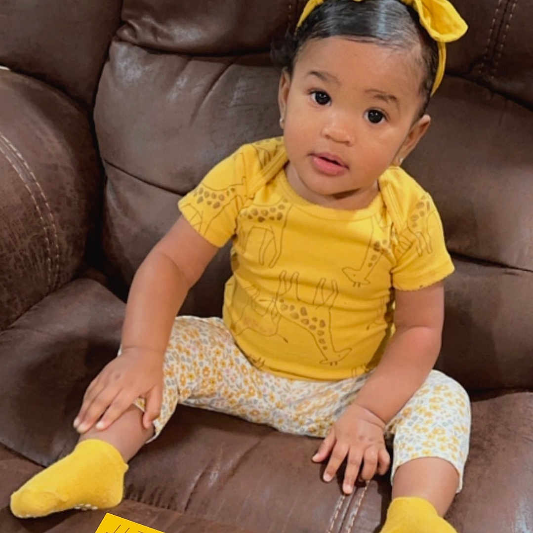 Mckinley is registered to the contest to win money with this photo: baby, chair, clothing, couch, cushion, face, furniture, happy, head, homedecor, hosiery, pants, person, photography, portrait, sitting, sleeve, smile, sock, t_shirt