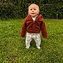 toddler, child, grass, outdoor, greenery, jacket, brown_jacket, pants, patterned_pants, standing, curious, blue_eyes, nature, daylight, young_child, person, cute, innocence, baby, casual_clothing