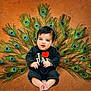 Erika joined the competition — help win amazing prizes! baby, child, infant, peacock_feathers, black_clothing, sitting, cute, portrait, indoors, colorful, decorative, expression, smiling, feet, hands, face, background, feathers, adorable, young