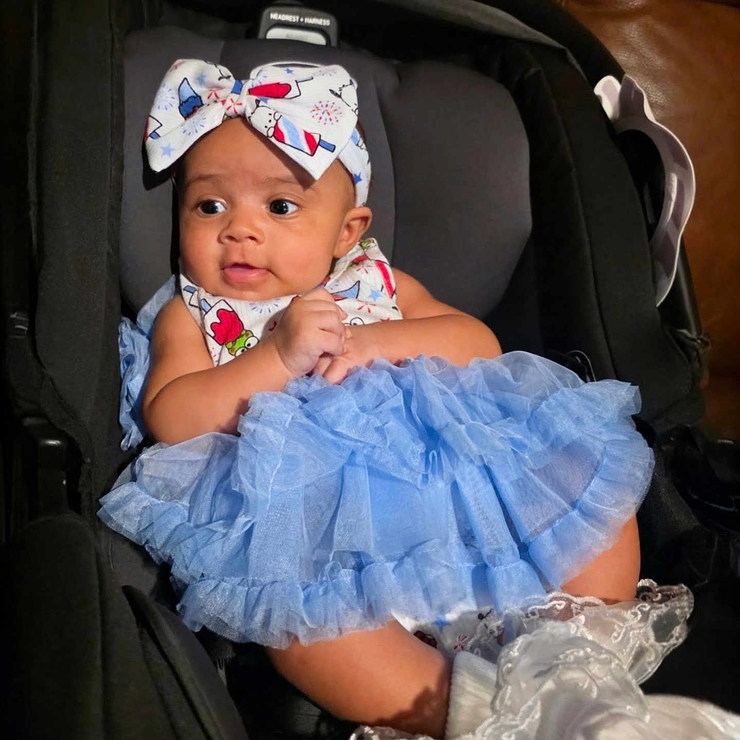 Anya is registered to the contest to win money with this photo: baby, child, car_seat, blue_tutu, headband, infant, clothing, cute, sitting, indoors, portrait, adorable, fashion, white_socks, lace, young, person, face, hands, seat