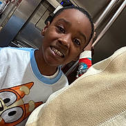 Aaron is registered to the contest to win money with this photo: child, smiling, pajamas, cartoon, indoor, kitchen, refrigerator, happy, person, clothing, face, head, hand, home, casual, portrait, young, playful, bright, expression