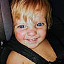 child, toddler, blue_eyes, blond_hair, smile, gap_tooth, car_seat, seat_belt, close_up, portrait, flash, rosy_cheeks, happy, indoors, baby_skin, head, hair, snapshot, phone_ui, timestamp