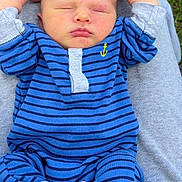 Koda is registered to the contest to win money with this photo: baby, sleeping, blue_striped_outfit, infant, grass, outdoor, person, legs, lap, relaxing, small_feet, cute, child, casual_clothing, newborn, peaceful, portrait, resting, human, natural_light