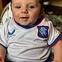 baby, child, infant, smiling, blue_eyes, white_jersey, blue_shorts, sitting, closeup, indoors, cute, portrait, chubby, hand, clothing, soft_lighting, happy, person, baby_fashion, comfortable
