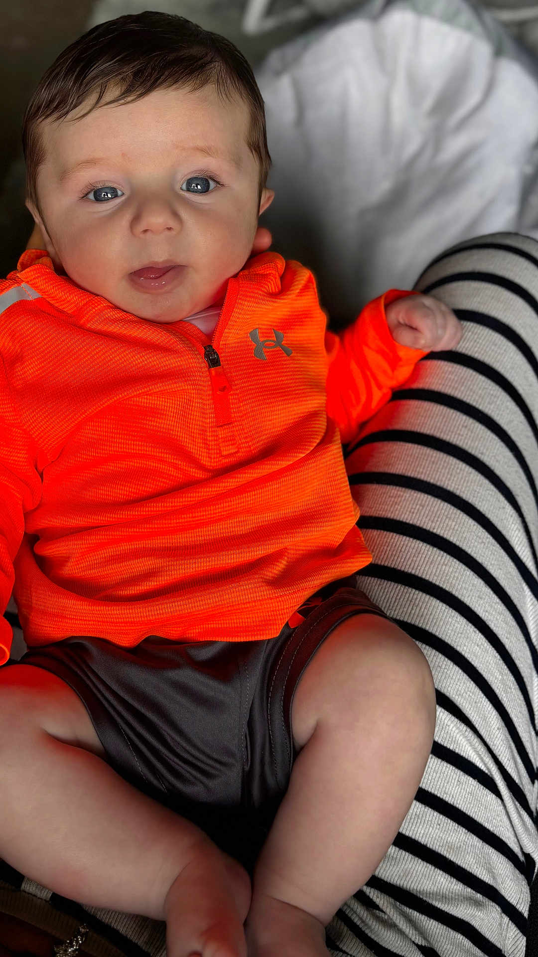 Luca is registered to the contest to win money with this photo: baby, child, infant, orange_clothing, under_armour, striped_pants, legs, face, blue_eyes, curly_hair, sitting, hand, skin, cute, portrait, indoor, person, holding, casual_clothing, young