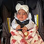 baby, infant, car_seat, headband, bow, blanket, pacifier, pacifier_clip, harness, straps, smile, chubby_cheeks, portrait, stroller, clothing, lacy_collar, pink_pattern, warning_label, cozy, evenflo
