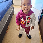 Maelle participe au concours pour gagner de l'argent avec cette photo : bed, blue_sheet, carpet, child, clothing, cute, door, floor, footwear, indoor, mickey_mouse, minnie_mouse, person, playful, room, slippers, smile, standing, toddler, young_child