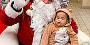 Maelle a rejoint le concours — aidez-le/la à gagner de superbes lots ! santa_claus, baby, child, costume, bear_costume, red_suit, white_beard, glasses, chair, holiday, christmas, decorations, wreath, gifts, candy_cane, indoor, floor_tiles, red_carpet, person, festive