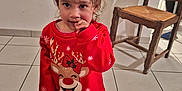 Maelle a rejoint le concours — aidez-le/la à gagner de superbes lots ! barefoot, child, christmas, curly_hair, cute, expression, face, floor, hand, indoor, pajamas, person, red_clothing, reindeer, shadow, standing, tile_floor, toddler, wall, wooden_chair