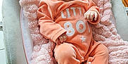 émiliana a rejoint le concours — aidez-le/la à gagner de superbes lots ! baby, infant, child, onesie, peach, pink_blanket, baby_seat, soft_texture, indoor, portrait, cute, small_hands, footed_pajamas, face, calm_expression, newborn, cozy, clothing, resting, comfort