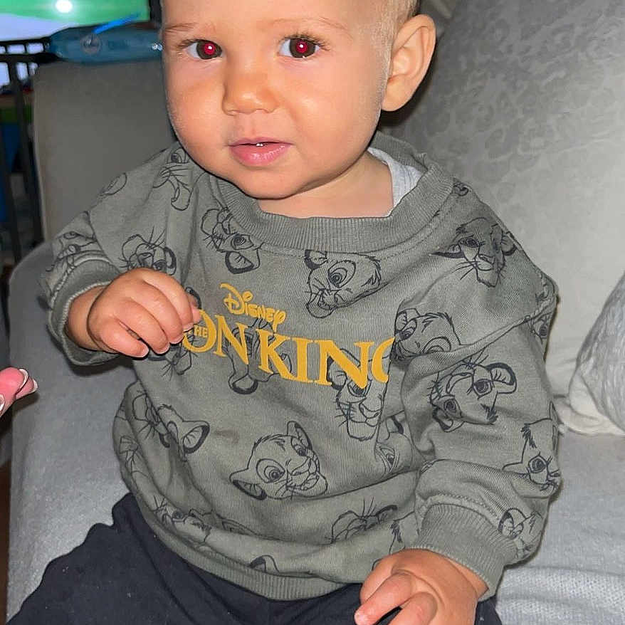 Aylan a rejoint le concours — aidez-le/la à gagner de superbes lots ! blanket, child, clothing, couch, curious, face, furniture, home, indoors, lion_king, nike, person, red_eye, short_hair, sitting, smile, sock, sweatshirt, television, toddler