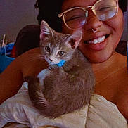 Queenie joined the competition — help win amazing prizes! person, smile, glasses, kitten, cat, blanket, indoor, cozy, cute, pet, happy, face, fur, collar, resting, snuggle, comfort, young_adult, portrait, relaxation