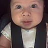 baby, child, infant, car_seat, seatbelt, strapped_in, wide_eyed, facial_expression, drool, portrait, close_up, indoors, vehicle, clothing, onesie, animal_print, sitting, face, eyes, safe