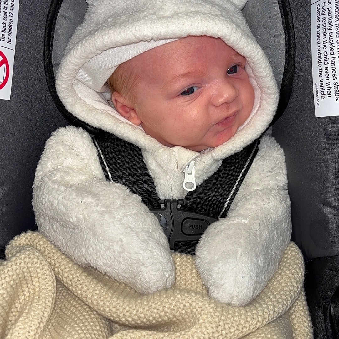 Jasper is registered to the contest to win money with this photo: baby, blanket, bonnet, cap, clothing, coat, cushion, face, hat, head, homedecor, hood, hoodie, jacket, knitwear, newborn, person, photography, portrait, sweater