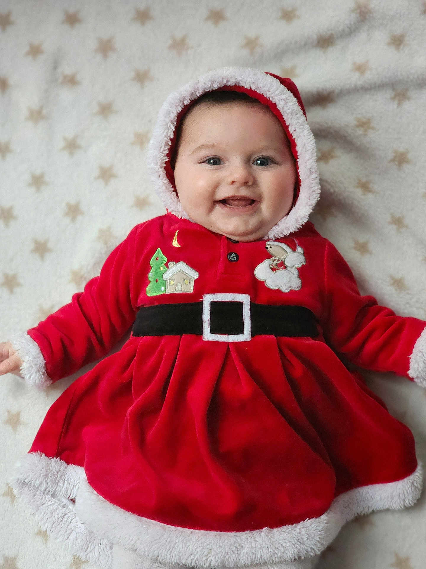 Anaïa participe au concours pour gagner de l'argent avec cette photo : baby, child, smiling, red_clothing, hood, blanket, stars_pattern, face, happy, cute, christmas, holiday, festive, fur_trim, portrait, infant, lying_down, indoors, cozy, warm