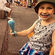 Maël a rejoint le concours — aidez-le/la à gagner de superbes lots ! bench, blue_ice_cream, boy, casual_clothing, child, daytime, food, fun, happy, hat, ice_cream, outdoor, people, plaid_shorts, sidewalk, smiling, street, summer, tank_top, urban
